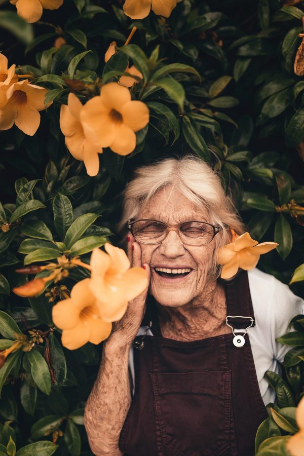 femme âgé qui rie au milieu des fleurs